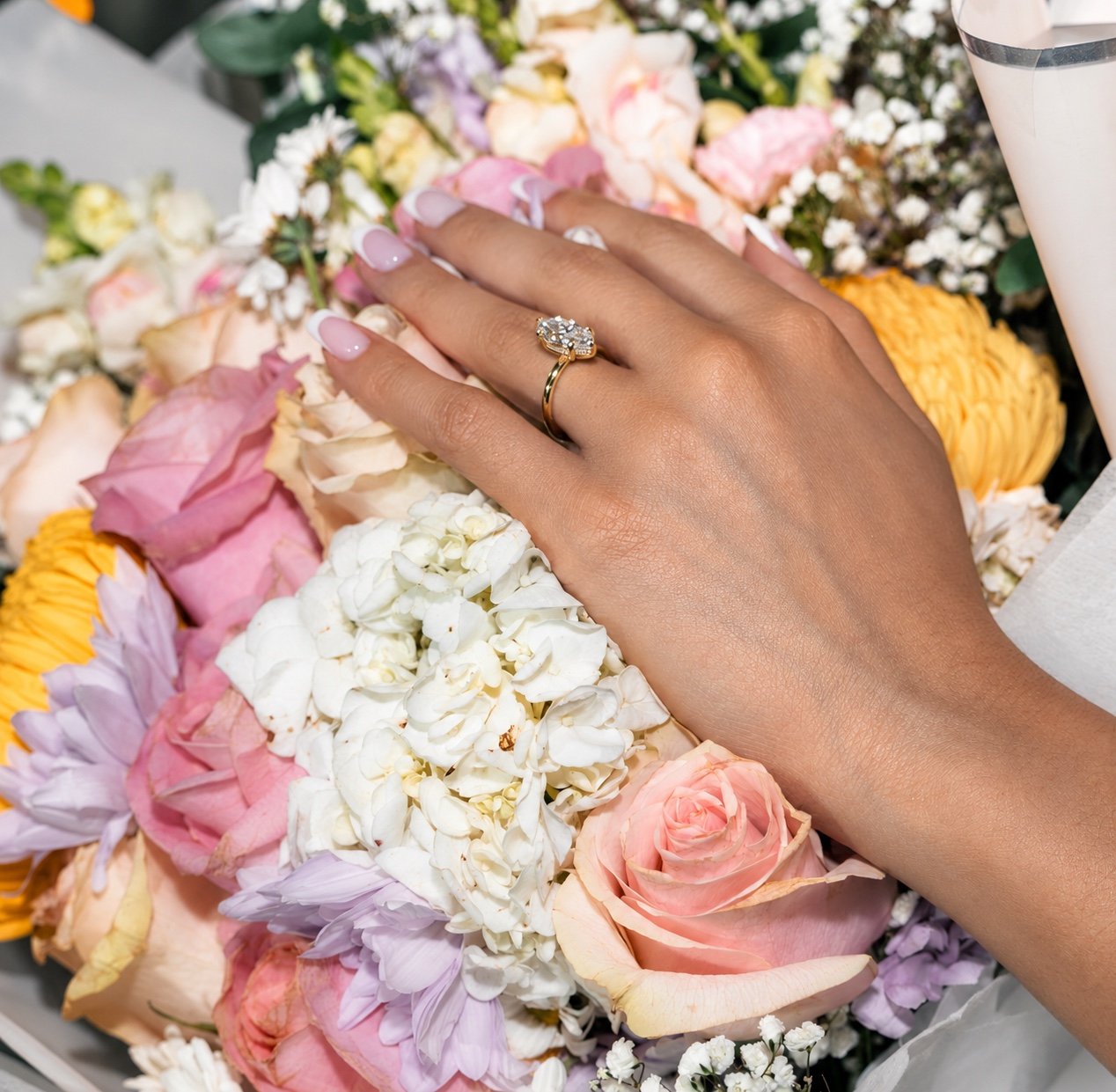 El anillo de compromiso en la mano de Sashalee sobre un ramo de flores.